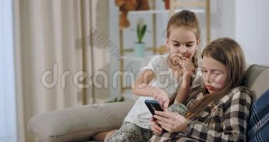 特<strong>写</strong>魅力和美丽的两个姐妹<strong>一起</strong>玩游戏，使用智能手机，而坐在沙发上。